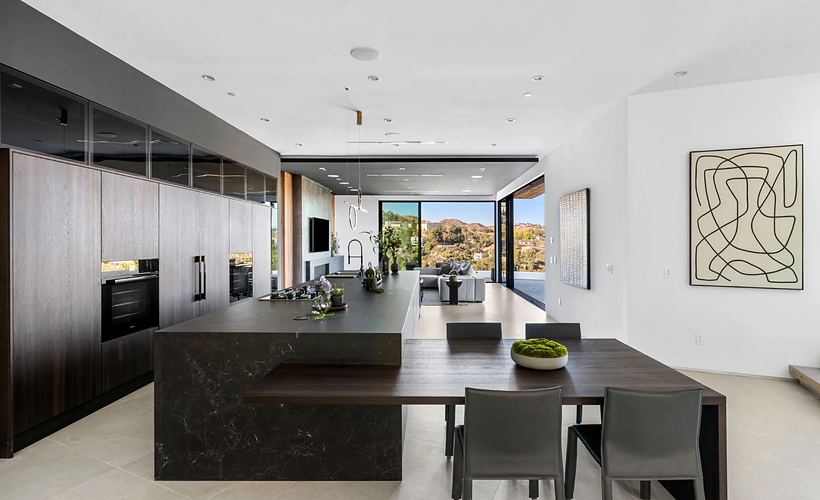 Cucina con colonne in legno scuro e isola effetto marmo nero con tavolo