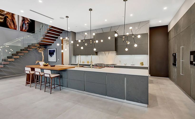 Cucina con isola effetto ardesia e schienale effetto marmo, sotto due lampadari